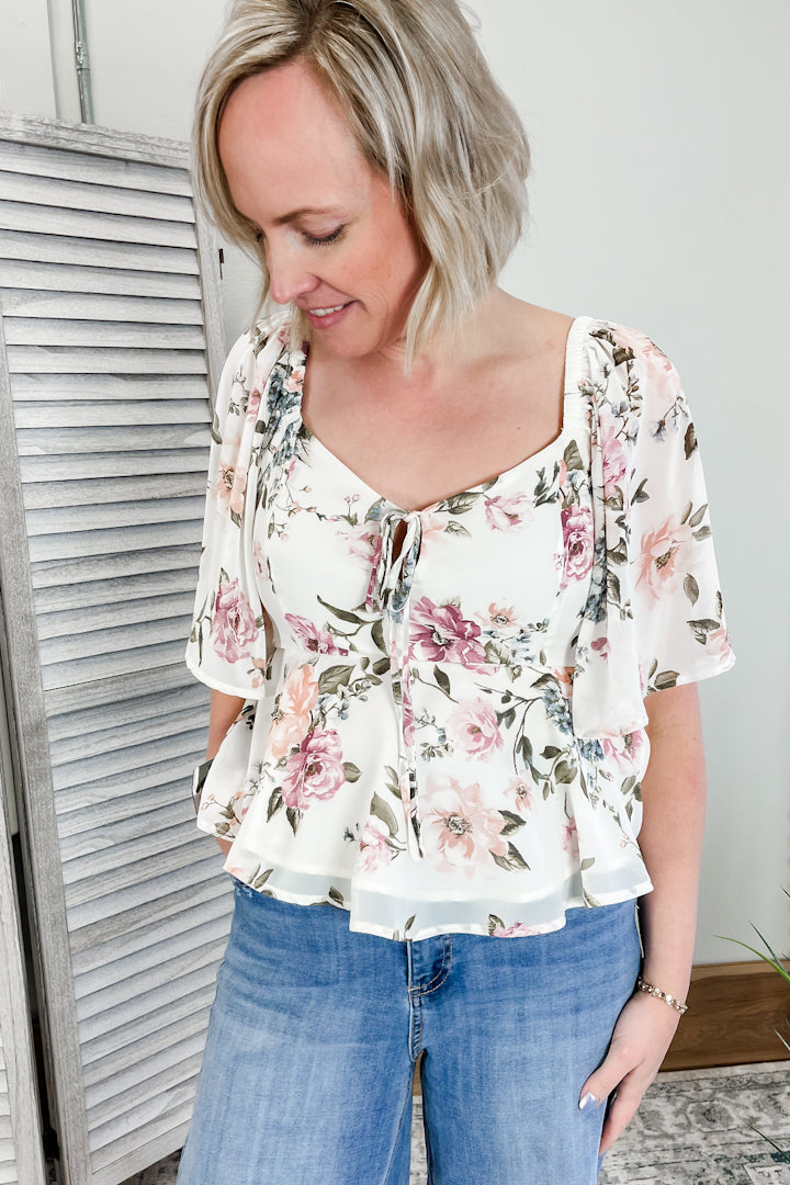 Women's floral top with flutter sleeves and tie front.