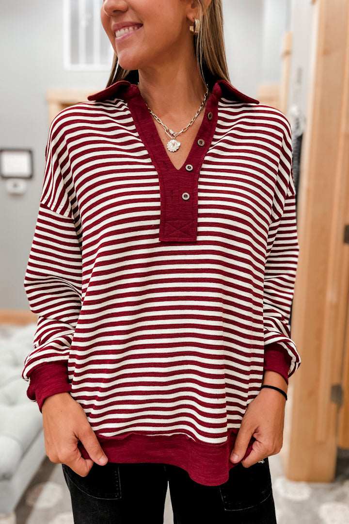 Person wearing a red and white striped shirt with collar and buttons