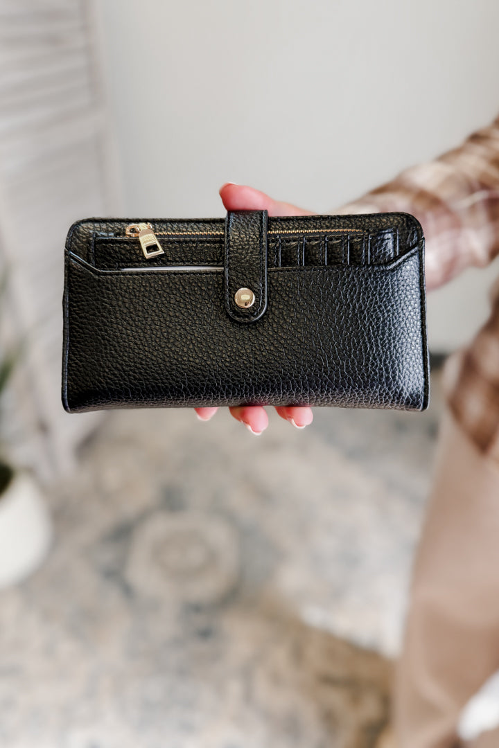 Black leather wallet held by a hand with a blurred background