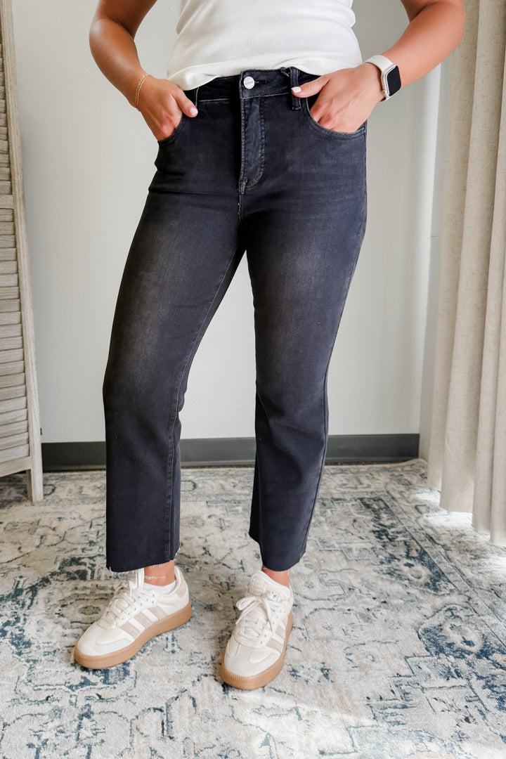 Person wearing black jeans and white sneakers on a patterned rug.