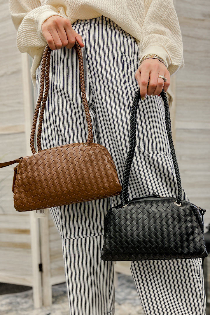 A small bag with a textured woven body, double braided shoulder straps, secure top zip with pull tabs, and gold-tone hardware accents