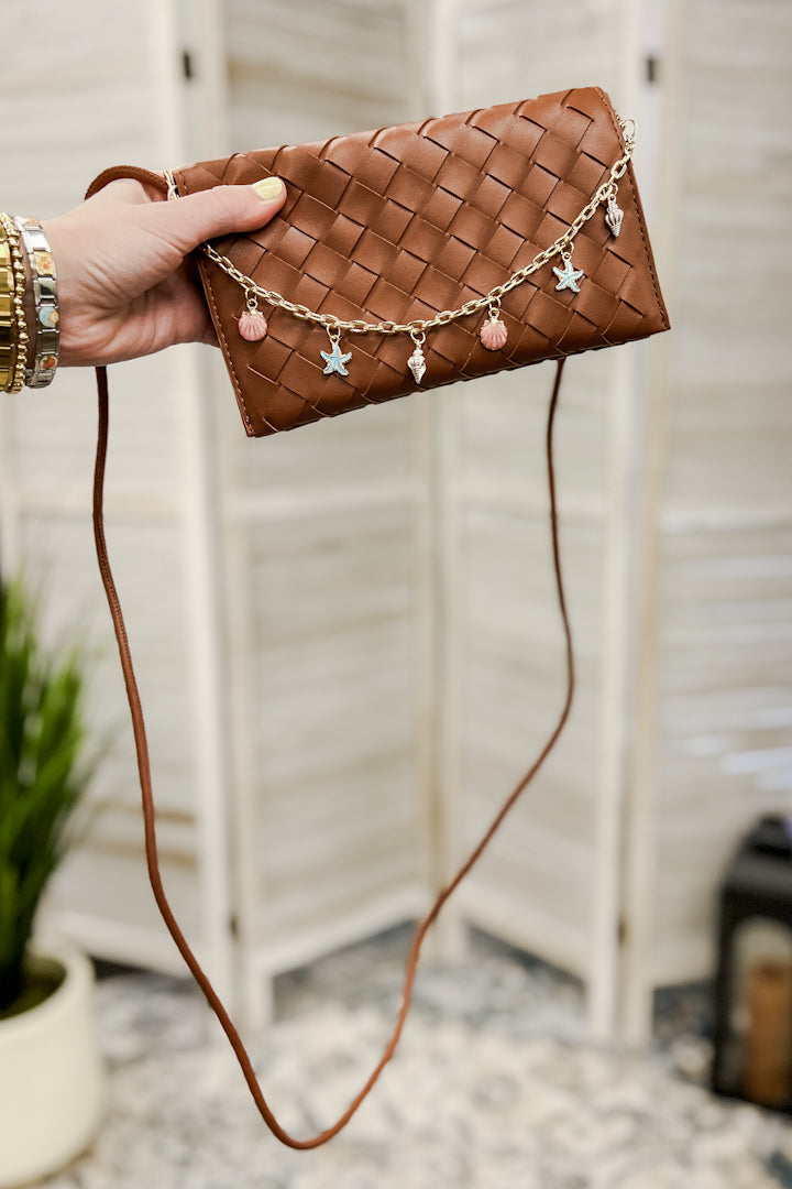 A woven slim envelope with a playful metal sea-inspired charm chain brown