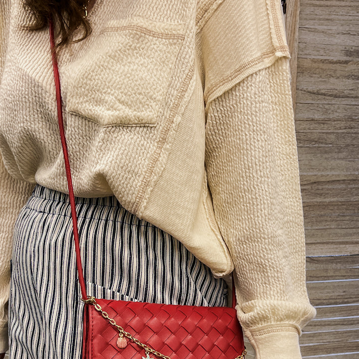A woven slim envelope with a playful metal sea-inspired charm chain red