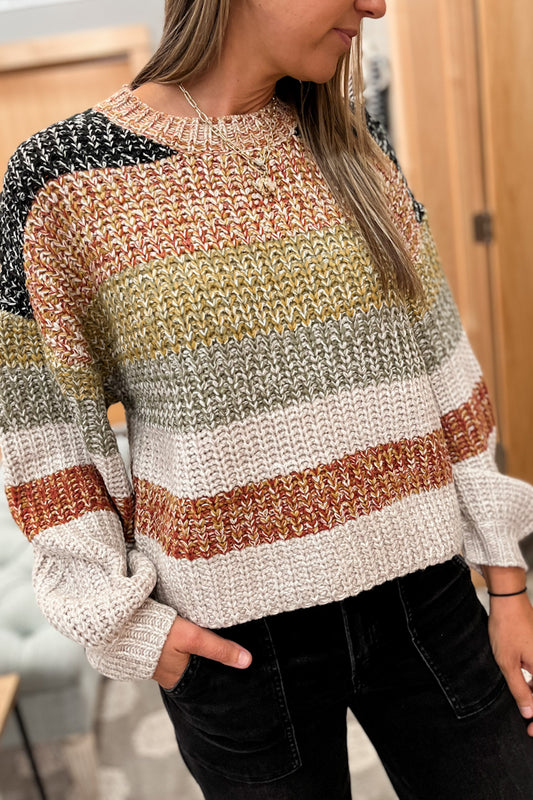 Person wearing a multicolored striped sweater with a blurred indoor background