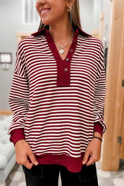 Person wearing a red and white striped shirt with collar and buttons