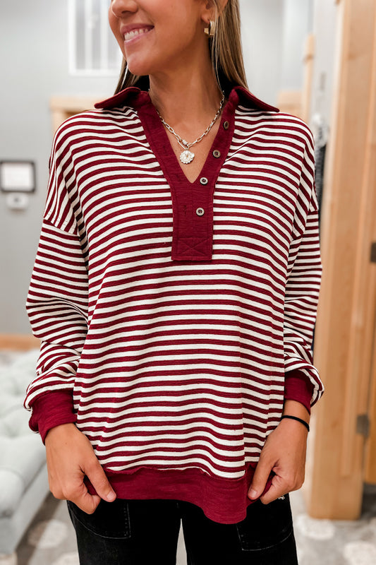 Person wearing a red and white striped shirt with collar and buttons