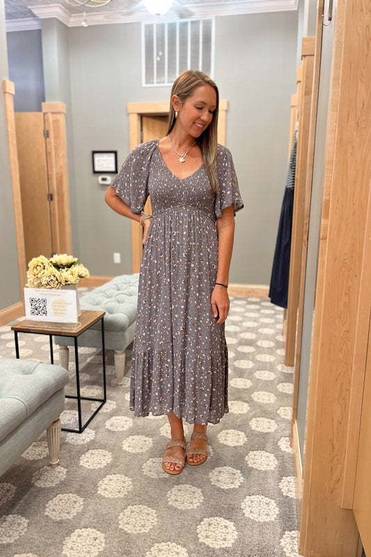 Woman trying on a floral dress in a fitting room.