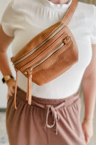 Person wearing a brown waist bag with a white shirt and pink pants.
