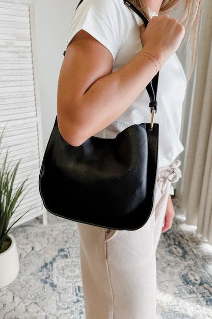 Person holding a black handbag indoors