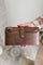 Brown leather wallet held by a person against a blurred background
