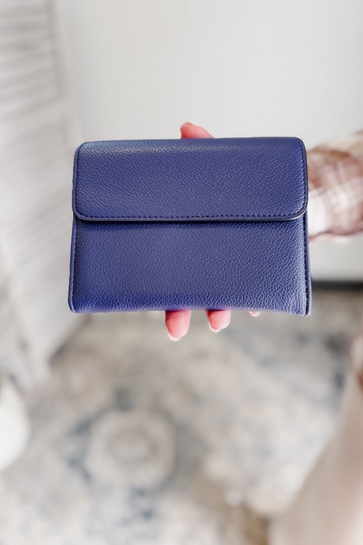 Blue wallet held by a hand against a blurred background