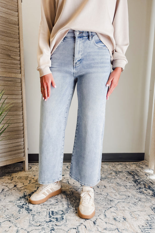 Person wearing light blue jeans and a beige sweater indoors.