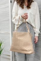 A slouchy woven silhouette with an interlaced textured exterior. It has a single knotted shoulder strap