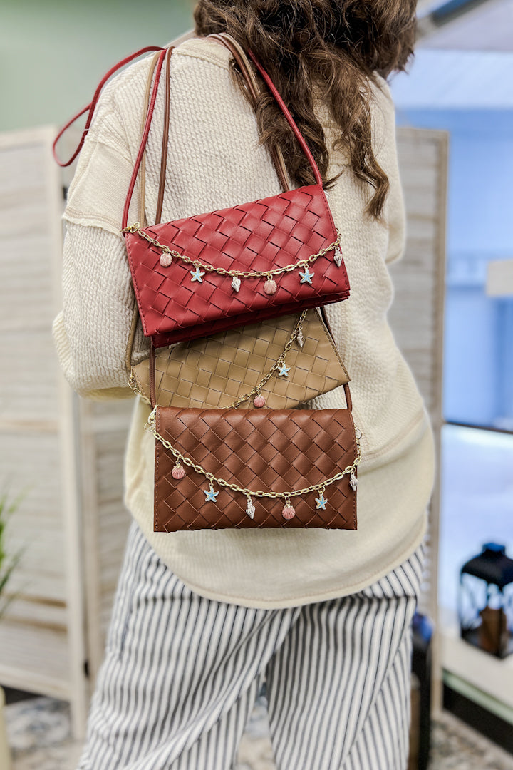 A woven slim envelope with a playful metal sea-inspired charm chain