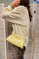 A small bag with an adjustable strap, top-frame closure and ring-tassel hardware yellow