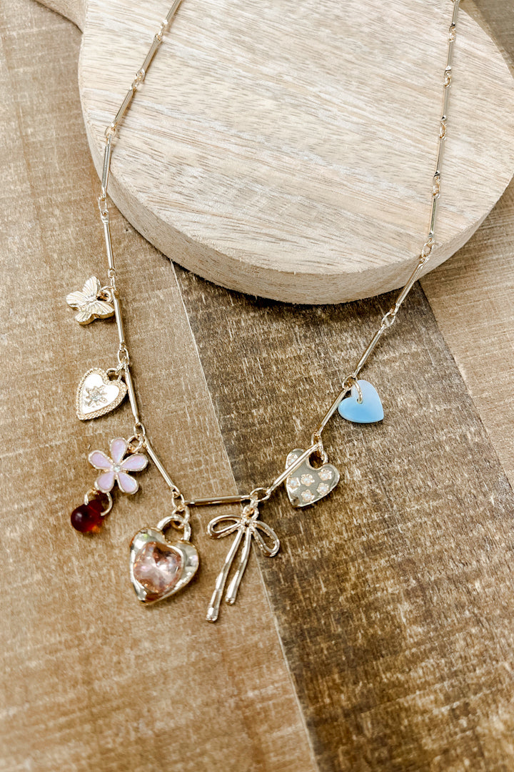 Featuring a delightful mix of charms—rhinestone heart, strawberry, flower, butterfly, and classic heart—all strung on a sleek gold-plated chain